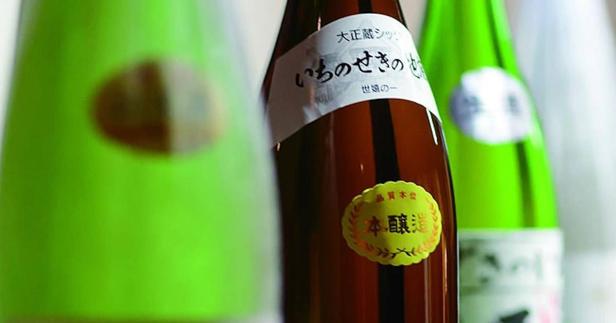 Sekinoichi sake bottle with green bottles behind it