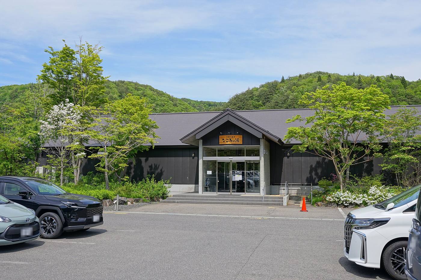 The entrance to Nagomi no Yu at Yamanokami Onsen beneath wooded hills.